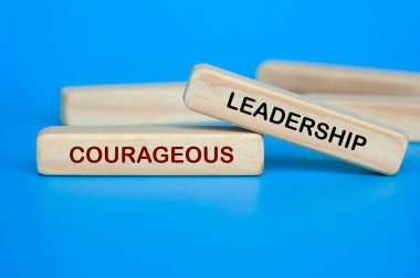 Wooden block on blue background showing COURAGEOUS LEADERSHIP text for confidence and strength