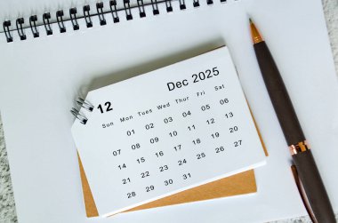 Not defteri ve kalem arkaplanındaki Beyaz Aralık 2025 takvimi