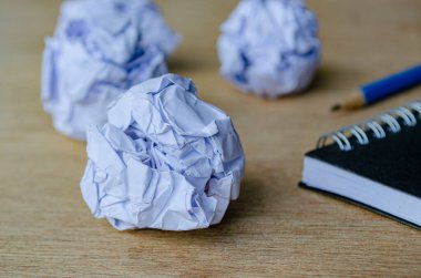 Sarmal defter ve kalemin yanında duran buruşuk kağıt parçalarının yakın plan görüntüsü