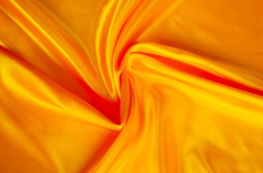 Pürüzsüz kıvrımları olan lüks altın ipek kumaş prim tasarımı için zengin soyut bir arkaplan oluşturuyor