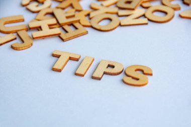 Beyaz arkaplan üzerinde ahşap harflerle oluşturulan ipucu metni tavsiye rehberliğini ve yardımcı bilgi kavramını temsil eder