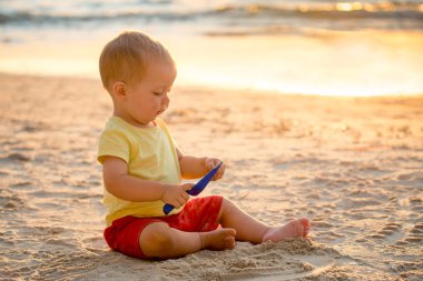 Sahilde oturup spade çocuk