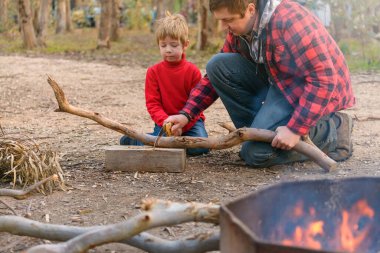 Babası, Güney Avustralya 'daki Kuitpo Ormanı' nda kamp ateşi için odun testeresiyle odun kesmesine yardım ediyor.