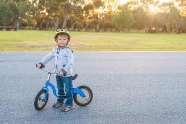 Güney Avustralya Adelaide Park Lands 'da gün batımında dengeli bisiklete binen bir çocuk.