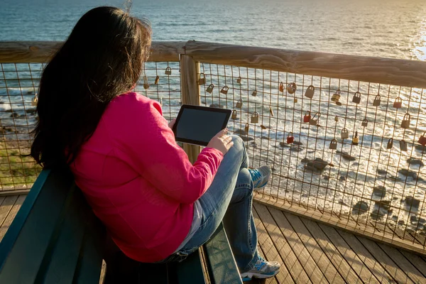 Frau benutzt Tablette am Strand bei Sonnenuntergang — Stockfoto