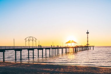 Günbatımında Brighton Jetty 'de yürüyen insanların siluetleri, Güney Avustralya
