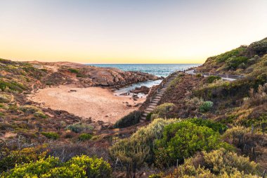 Green Bay Sahili 'nin muhteşem günbatımı manzarası dramatik granit çıkıntıları ve sıcak altın ışıklarıyla, Port Elliot, Güney Avustralya.