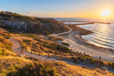 Gün batımında OSullivan Sahili sahil şeridi, Sahil şeridinde bisiklet yolu ve sıcak altın ışıkta yıkanan yürüyüş yolu, Güney Avustralya