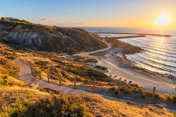 Gün batımında OSullivan Sahili sahil şeridi, Sahil şeridinde bisiklet yolu ve sıcak altın ışıkta yıkanan yürüyüş yolu, Güney Avustralya