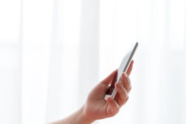 Cep telefonu pencerenin önünde tutan kadın