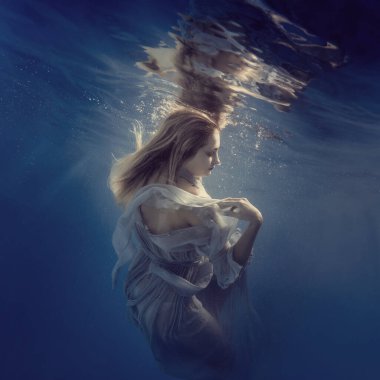 Suyun altında elbiseli bir kız ağırlıksız uçuyor gibi görünüyor.
