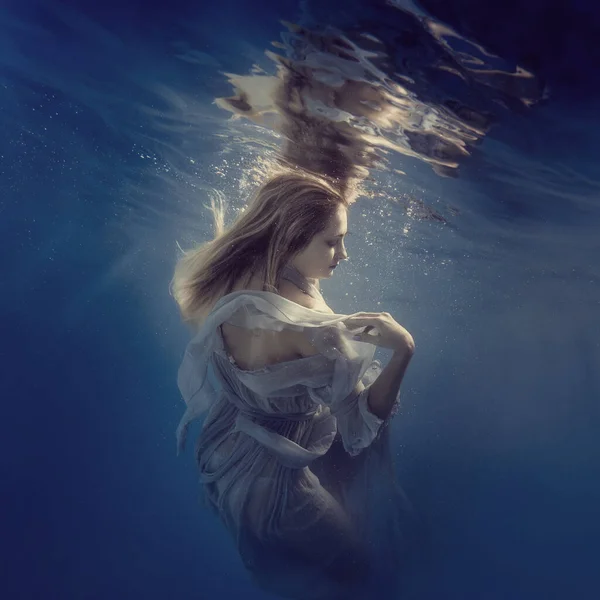 A girl in a dress underwater seems to fly in weightlessness