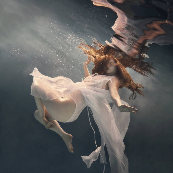 A girl in a white fluttering dress floats as if she were flying