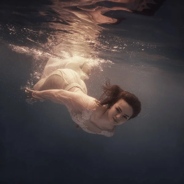 머리를 여자가 무중력 상태에서 떠다니는 것처럼 어두운 배경에서 물속을 헤엄친다 — 스톡 사진