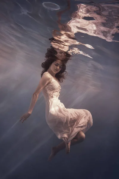 드레스를 머리를 여자가 무중력 상태에서 떠다니는 것처럼 물속을 수영한다 — 스톡 사진