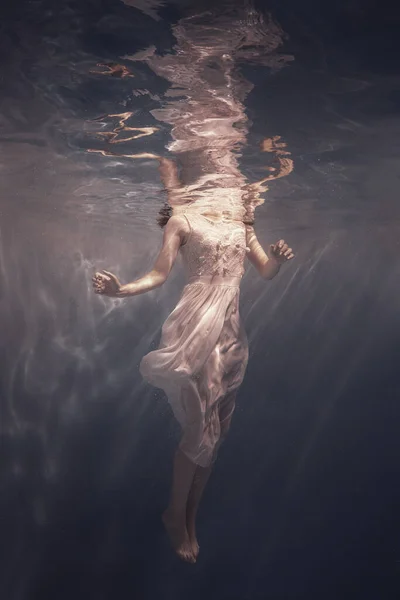 Dziewczyna Białej Sukience Długimi Ciemnymi Włosami Pływa Pod Wodą Jakby — Zdjęcie stockowe