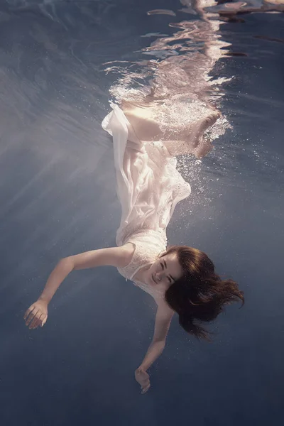 드레스를 머리를 여자가 무중력 상태에서 떠다니는 것처럼 물속을 수영한다 — 스톡 사진
