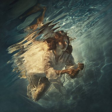 Beyaz dantel elbiseli bir kız, sanki yer çekimsiz havada yüzer gibi suyun altında yüzer.