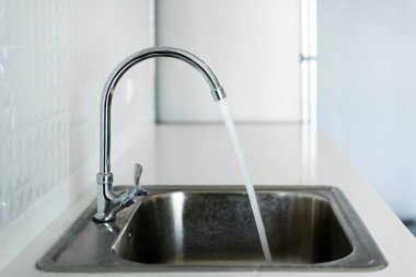 Modern beyaz mutfakta çelik lavabo, temiz iç tasarım.