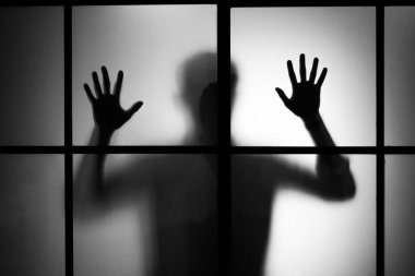 Buzlu cam kapının arkasında duran adamın silueti.