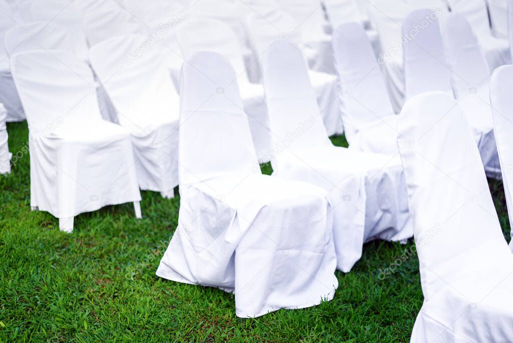 Rows of empty white folding chairs sitting on a lawn in Wedding ceremony event