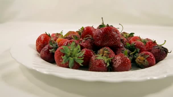 Fresas en un plato sobre un fondo blanco . — Vídeo de stock