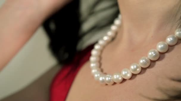 Девушка выпрямляет волосы на фоне ожерелий — стоковое видео