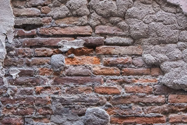 Kırık alçıyla kaplı eski tuğla duvar..