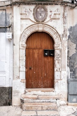 Binaya kemerli giriş. Taş kapı, kapalı ahşap kapı, veranda. Monopoli, İtalya.