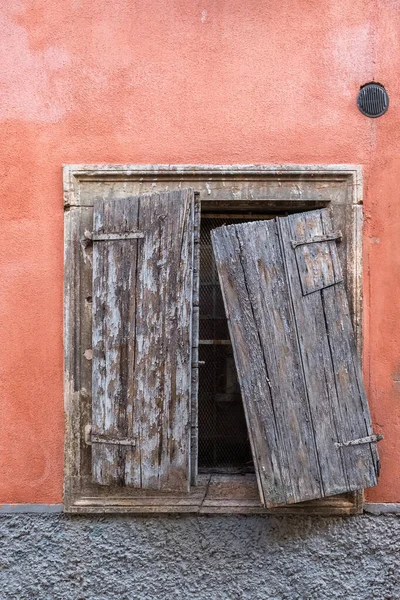Taş bir duvardaki yalnız bir pencere, kırık bir ahşap kepenkle kapatılmış..