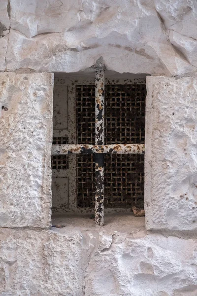 Taş duvarda metal ızgara olan küçük bir pencere..