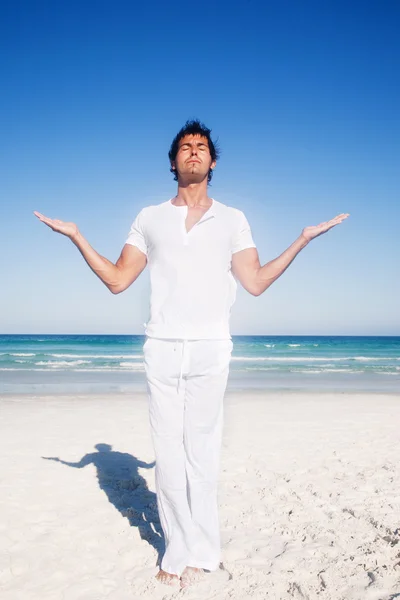 man meditating on the beach