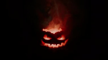 Şeytani balkabağı Jack ileriye bakıyor. Cehennem ateşi yavaşça başını yakıyor..