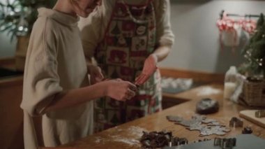 Anne ve kızı mutfakta hamur işleri hazırlıyorlar. Gülümseyen bir anne, dilimlenmiş kurabiyeleri kızına verir..