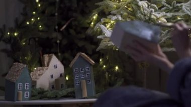 Yeni yıl ve Noel için el yapımı güzel bir dekor hazırlıyorum. Kadın eli. Minyatür bir evi boyama süreci. Arka planda güzel bir minyatür şehir görünüyor.