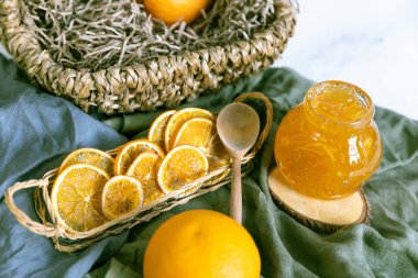 Ahşap bir standa portakal reçeli ve tahta bir kaşık ve kurutulmuş portakalla tekstil. İçinde bir sepet dolusu portakalla. beyaz arkaplan