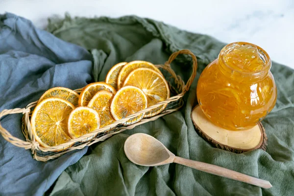 Ahşap bir stantta, ahşap bir kaşık ve kurutulmuş portakalla tekstil reçeli..
