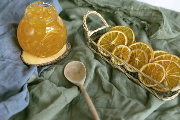 Ahşap bir stantta, ahşap bir kaşık ve kurutulmuş portakalla tekstil reçeli..