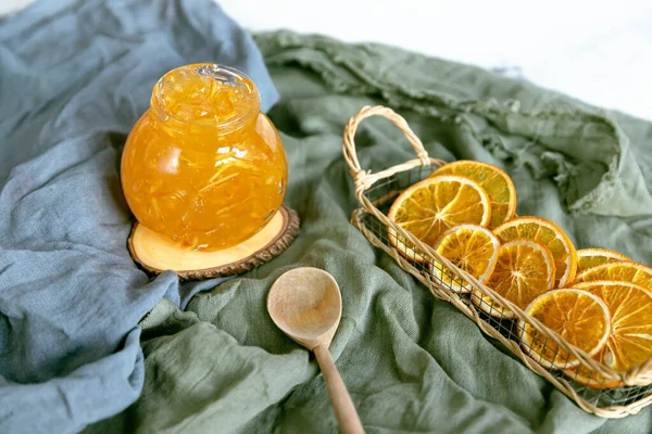 Ahşap bir stantta, ahşap bir kaşık ve kurutulmuş portakalla tekstil reçeli..