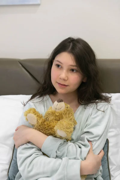 Teenage girl in pyjamas with a Teddy bear on Sunday morning