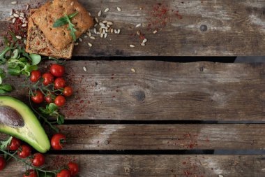  Uzayı kopyala Ahşap bir arka planda, solda, kiraz domatesleri, avokado, sarımsaklı çörek, şifalı otlar ve ayçekirdeği sebzelerle serilir. Sağlıklı beslenmenin kırsal tarzı