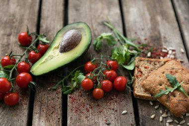 Kırsal çerez. Sebzeler, kiraz domatesleri, avokado, yeşil ayçekirdeği ve yumuşak taze ekmekler. Her şey taşralı tarzında döşenmiş.