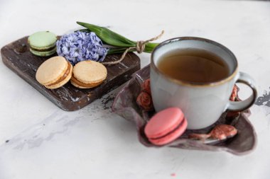 Ahşap zemin üzerinde badem kurabiyeli kahvaltı çayı, sümbül çiçeği ve güzel bir çay tabağı. yatay yönelim