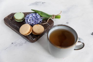 Ahşap zemin üzerinde badem kurabiyeli kahvaltı çayı, sümbül çiçeği ve güzel bir çay tabağı. yatay yönelim