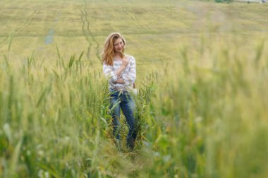 Bir kız, çayırdaki çavdar tarlasında duruyor. Yazın bir çiçek tarlasında.                           