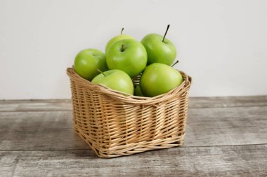 Tahta bir masada sepette yeşil elmalar