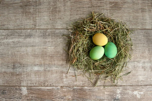 Bunte Eier Korb Mit Stroh Auf Der Hölzernen Tischplatte — Stockfoto