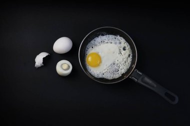 Kızarmış yumurta kabuğu, siyah bir arka planda kızartma tavasında.                               