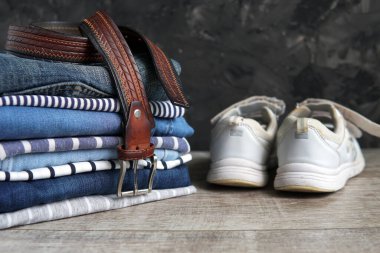 jeans belt a stack of clothes sneakers shoes on the shelf                              