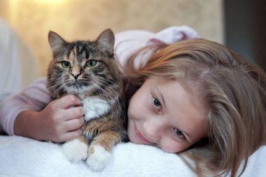 Şirin kız ve kedi kanepede uzanıp sarılıyorlar. Hayvanlar için sevgi. Dikkat